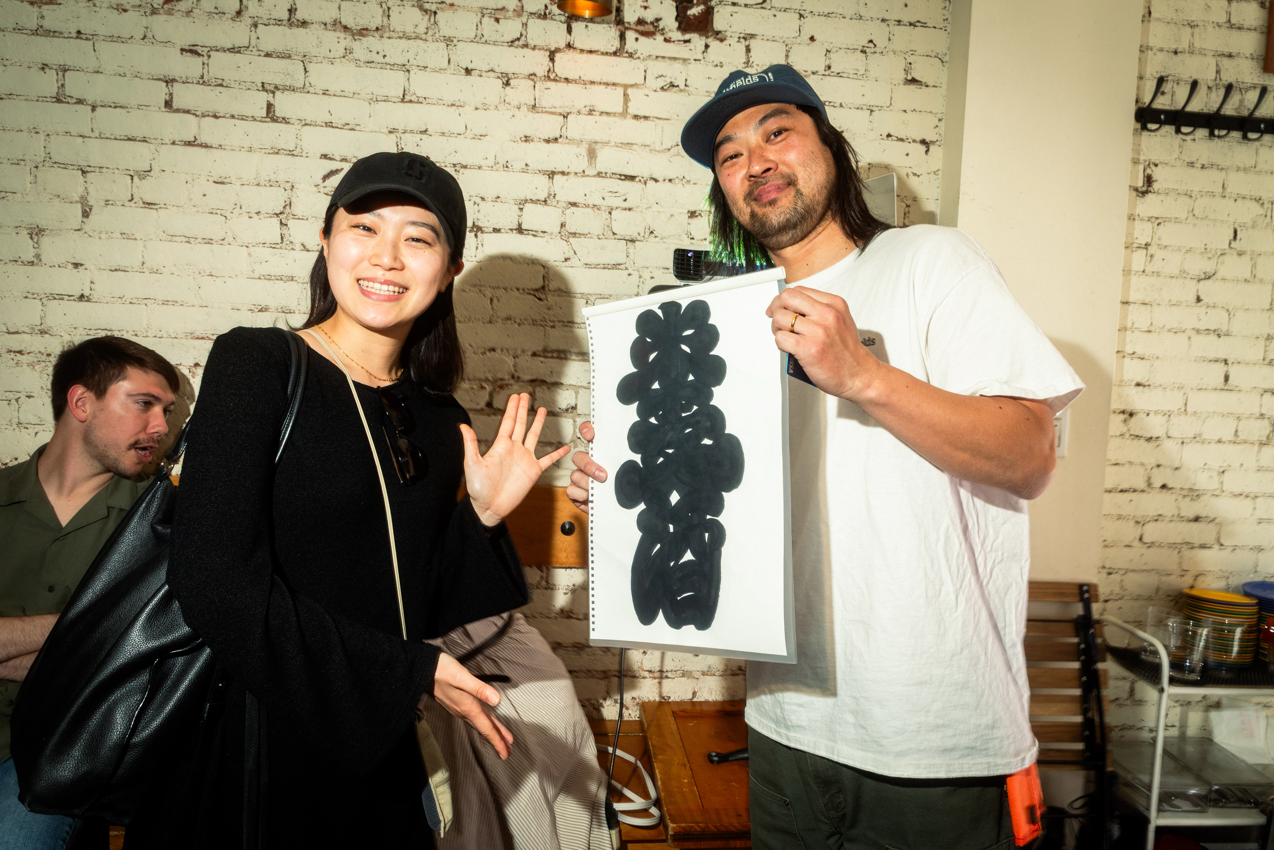An artist and guest holding artwork at the launch party